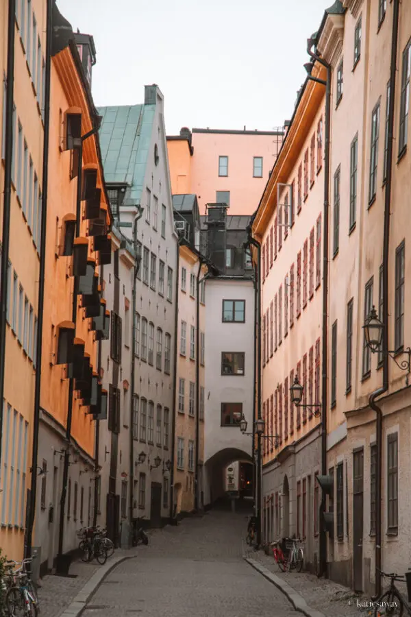 An alley way in Gamla Stan in Stockholm with a white house and tunnel at the end