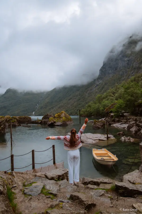 A person standing by Bondhusvatnet lake with a yellow row boat and view of the glacier