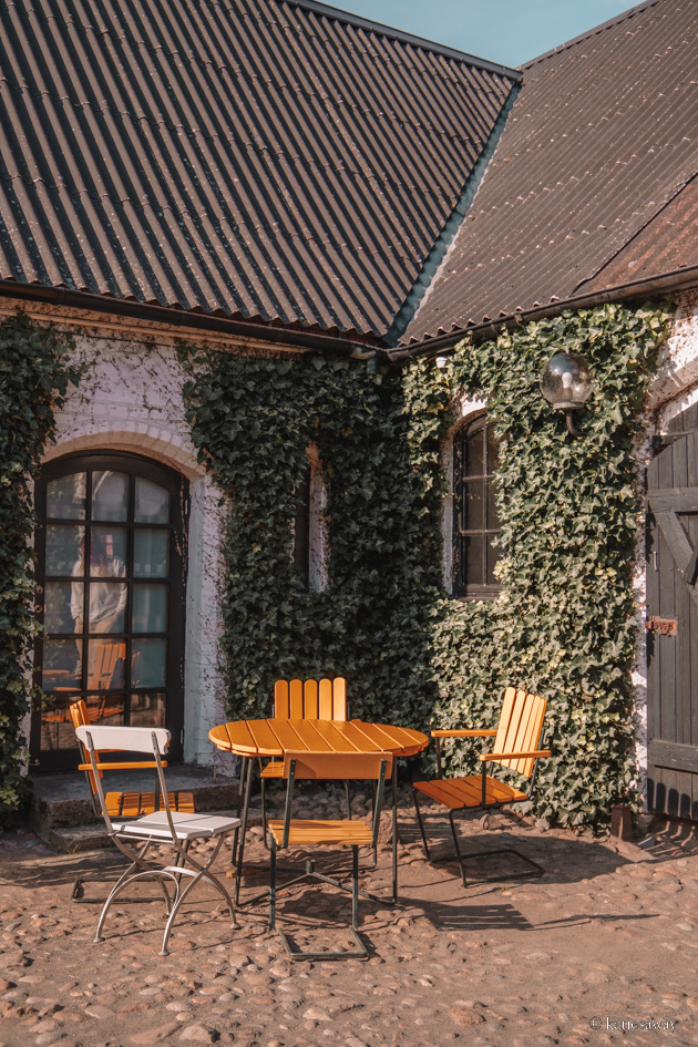 The outdoor seating area of Olof Viktos with an old stone building covered in leaves