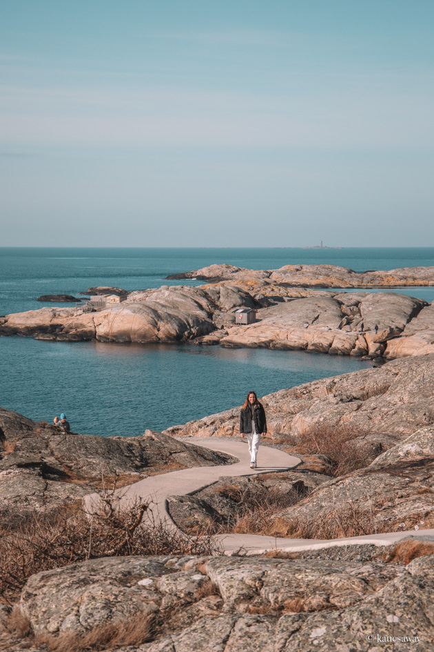 girl walking down a windy path along cliffs with water and sea in the background