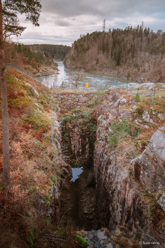 girl in a yellow raincoat walking over a cliff bridge by the trollhättan hydroplant