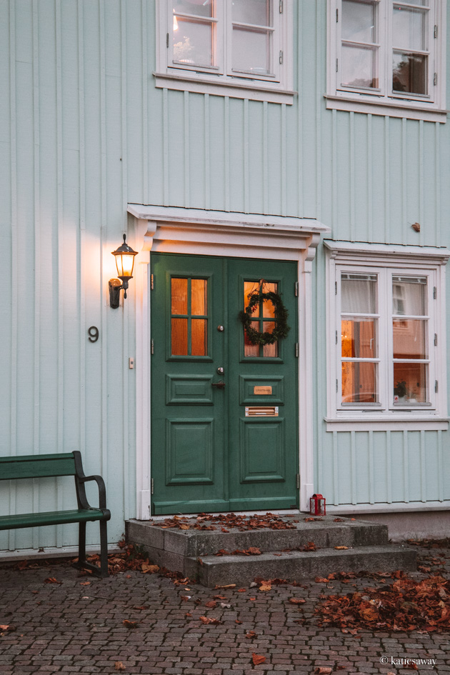 a green door with a christmas wreath on a blue wooden house in kungälv