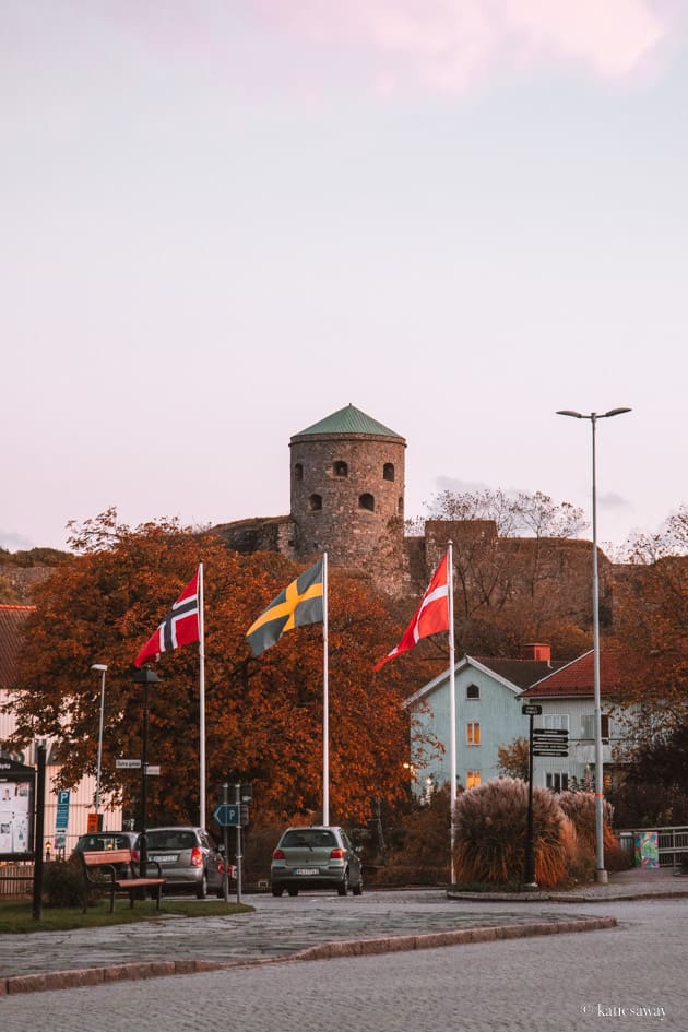 bohus fästning in the distance with a swedish, norwegian and danish flag in the foreground.