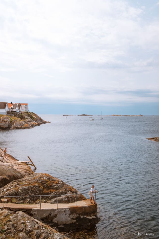 girl standing on a pathway that loops around a rock down by the water in klädesholmen