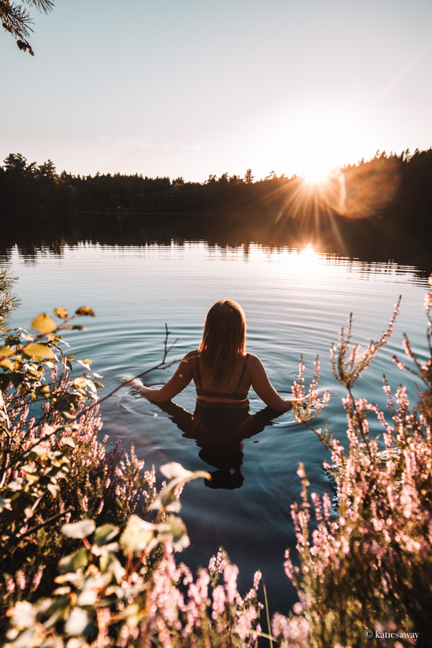girl swimming in a lake at sunset surrounded by pink flowers
