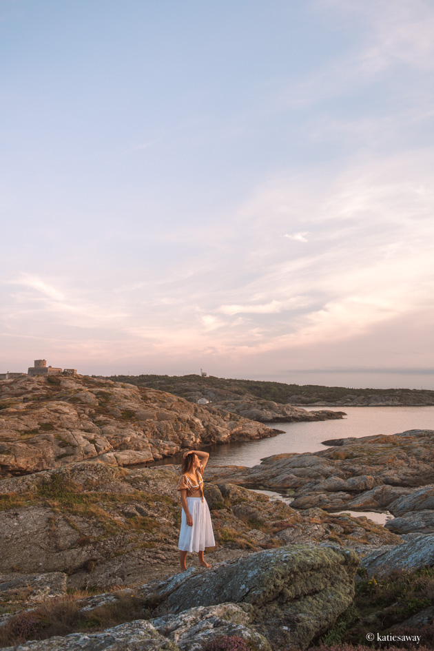 girl standing on a rock at sunset with the island of marstrand and carlstens fâstning in the background