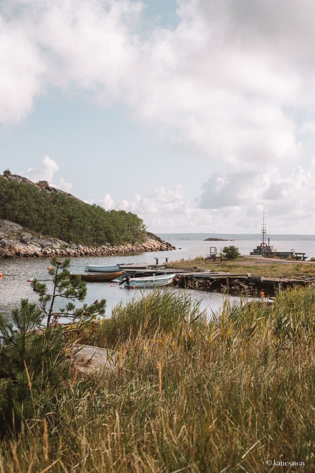 djupvik badplats vrångö seen from behind a grassy hill with the dock and boats in the background