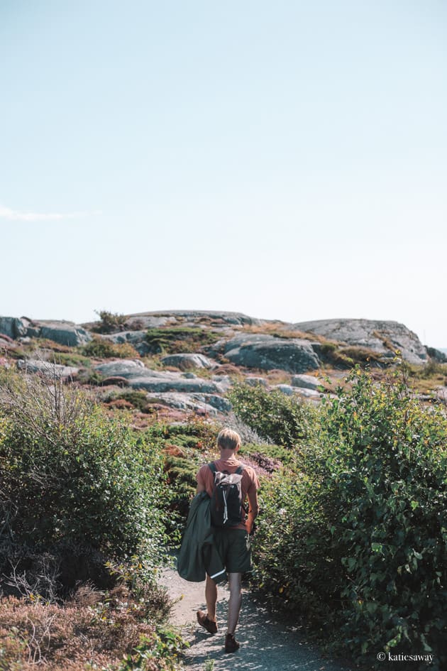 man in a red shirt with a backpack walking down the Södra Slingan Hike Vrångö