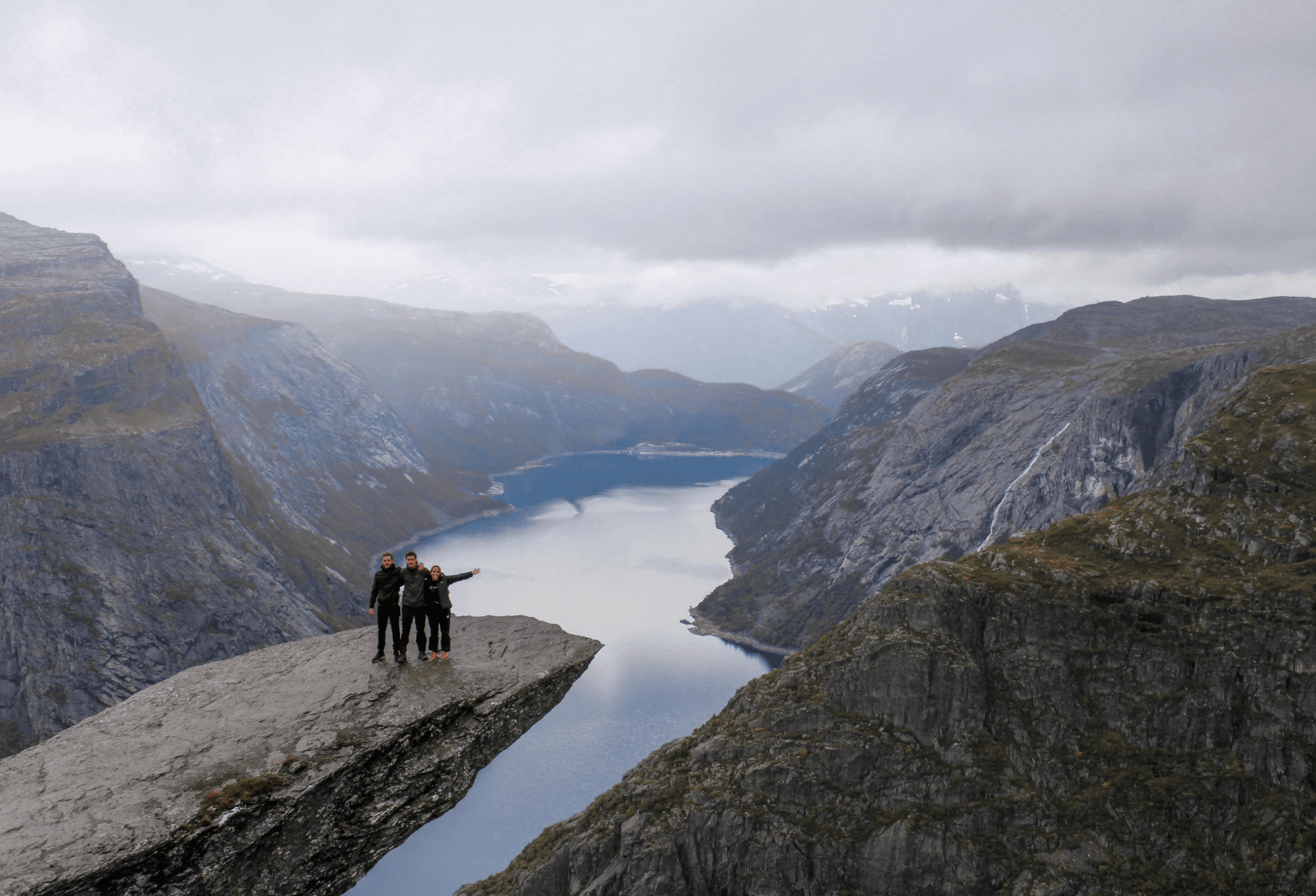 three people standing on trolltunga in september