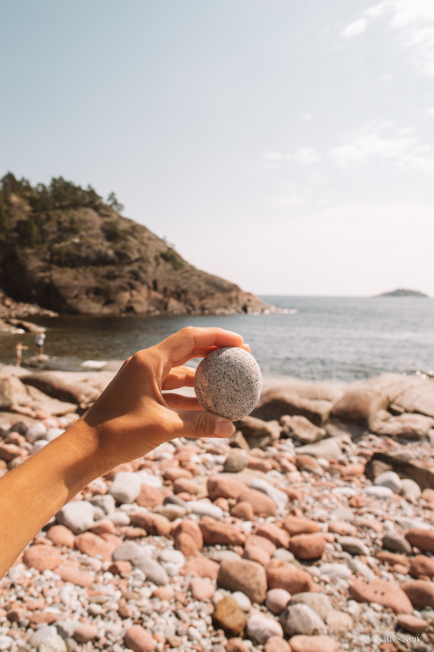 hand holding up one of the spherical rocks on storviken beach