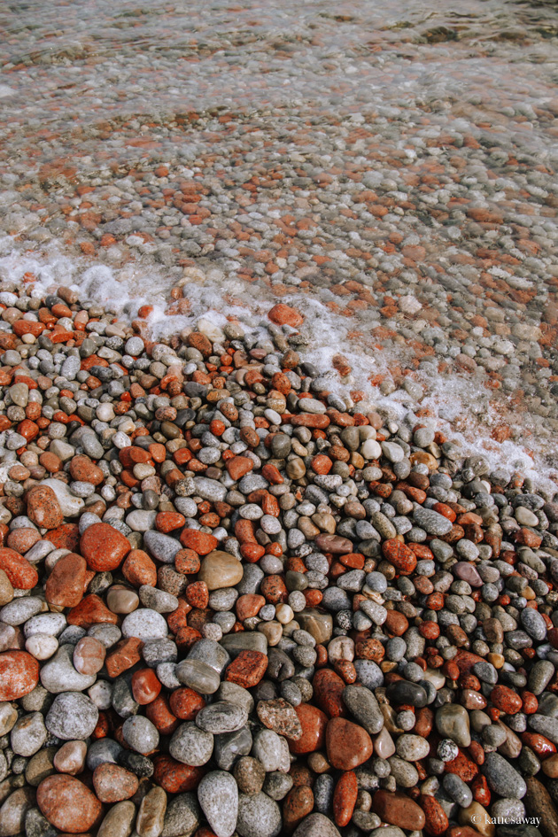 red, grey, white and black circular rocks with water flowing over the top