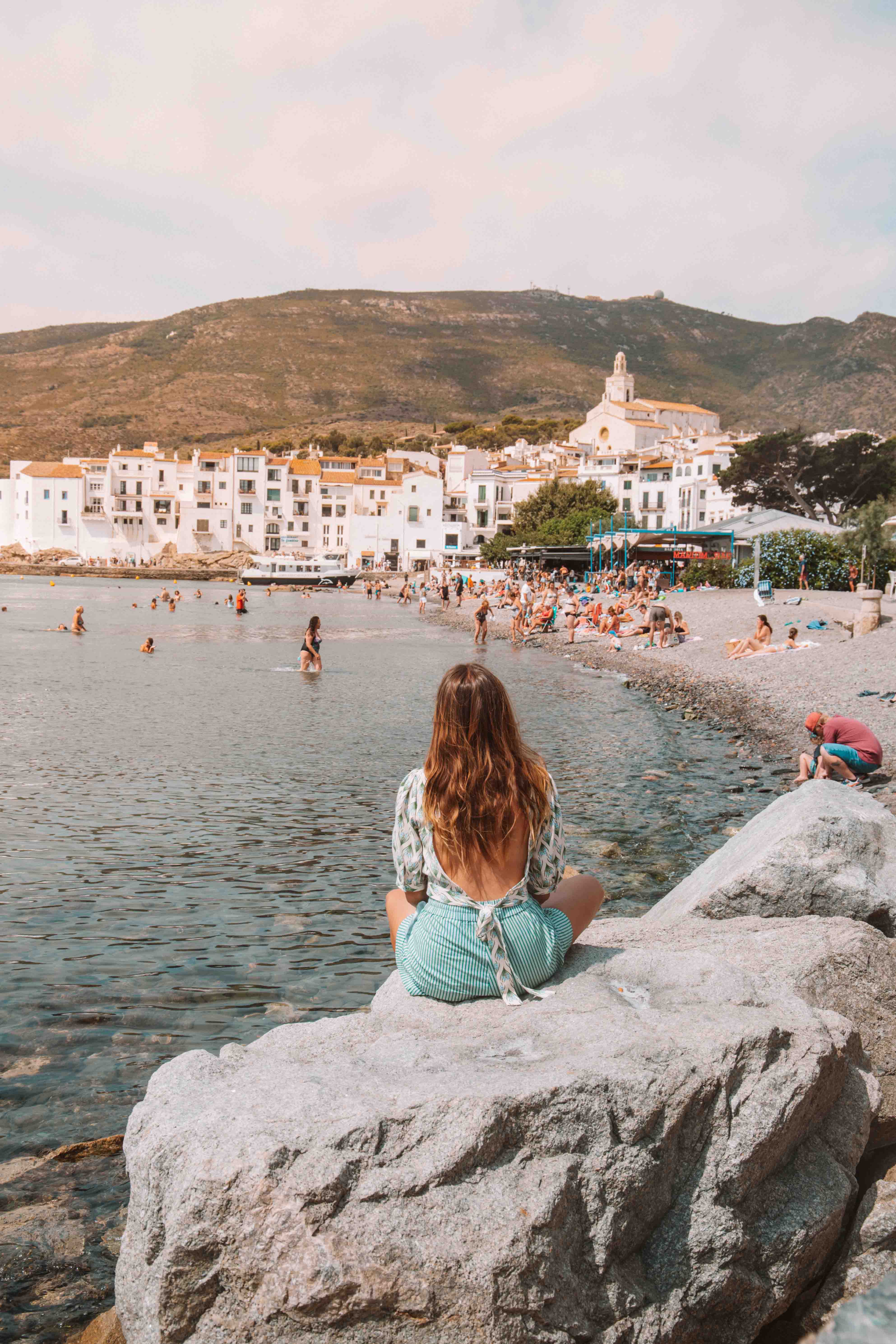 girl sitting by platja gran in cadaques