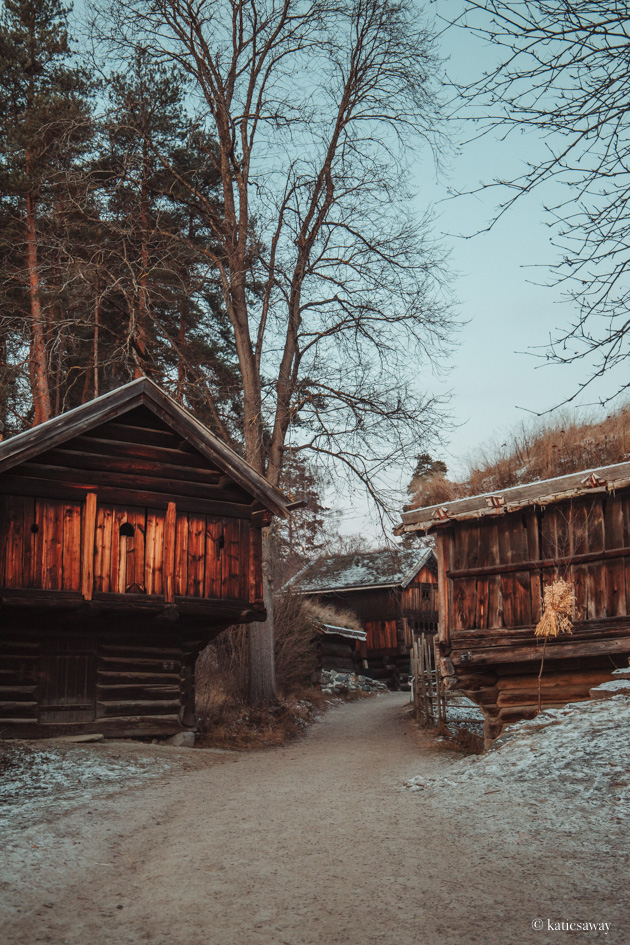 Two timber buildings inside the Norwegian folk museum in Oslo during winter covered in snow and ice