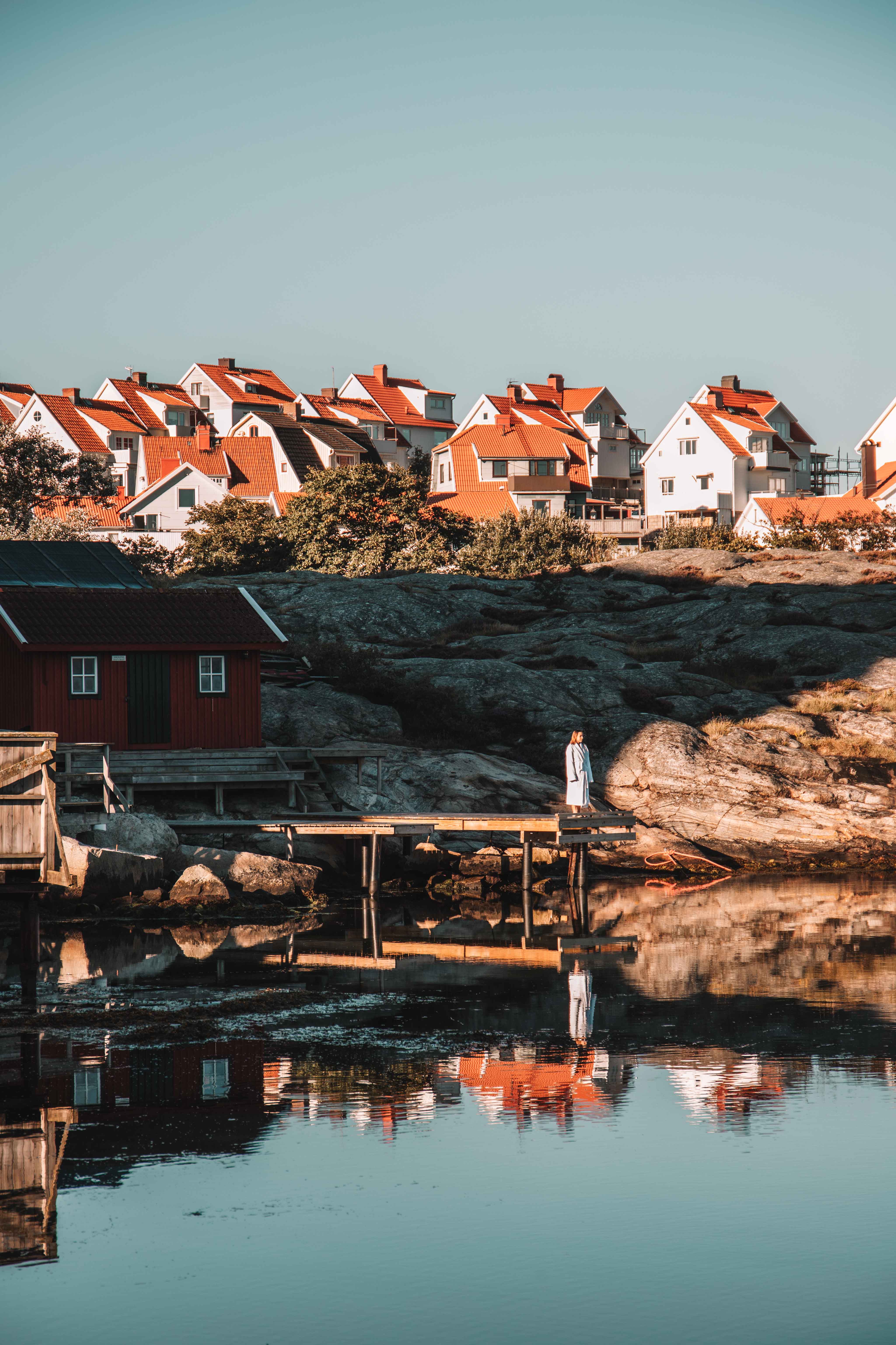 Man standing at the edge of the bridge into the water at sunset on the cliffs in Smögen