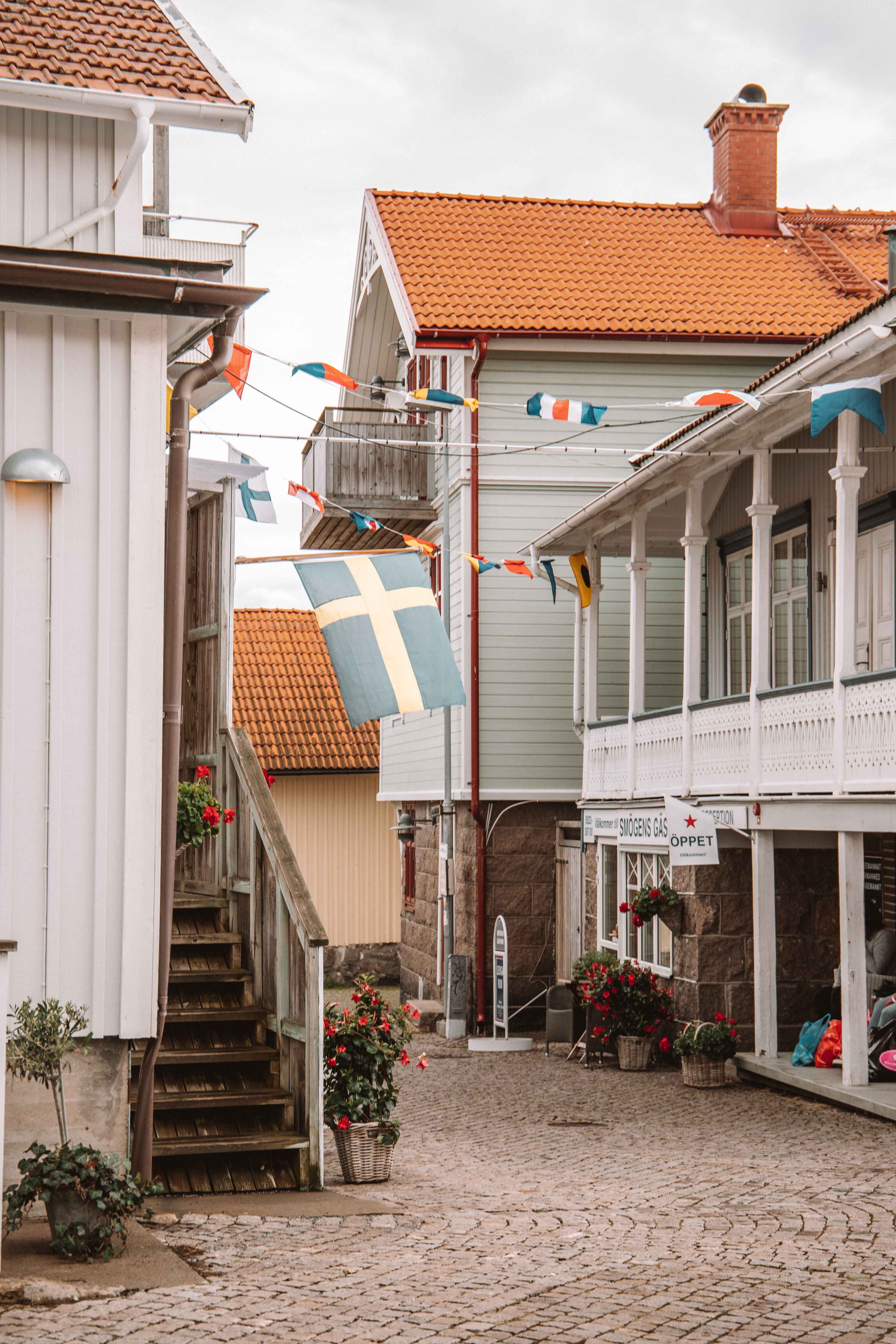 a small street with wooden houses and flags hanging between on the island of Smögen