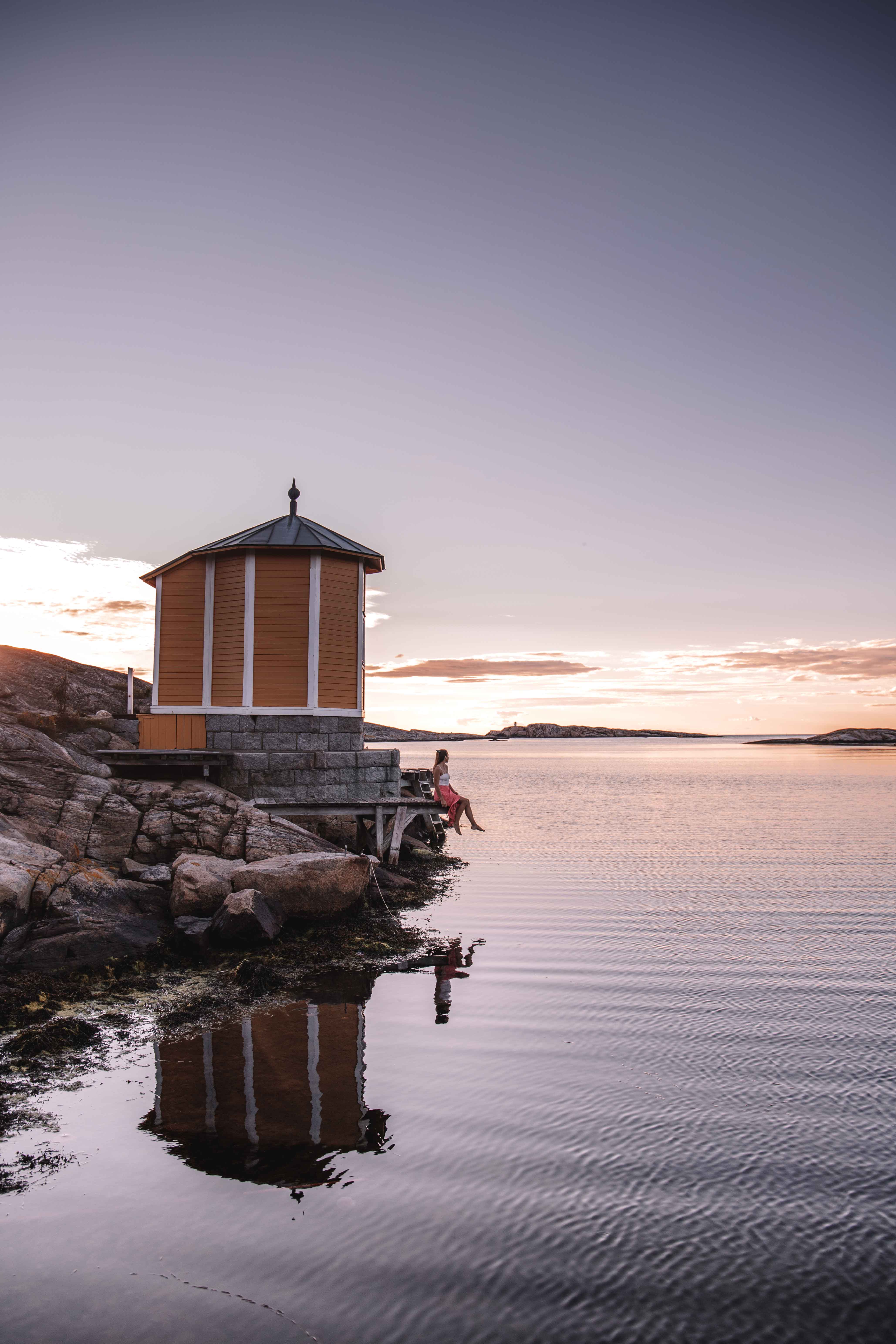girl sat by a boat house at sunset on Smögen