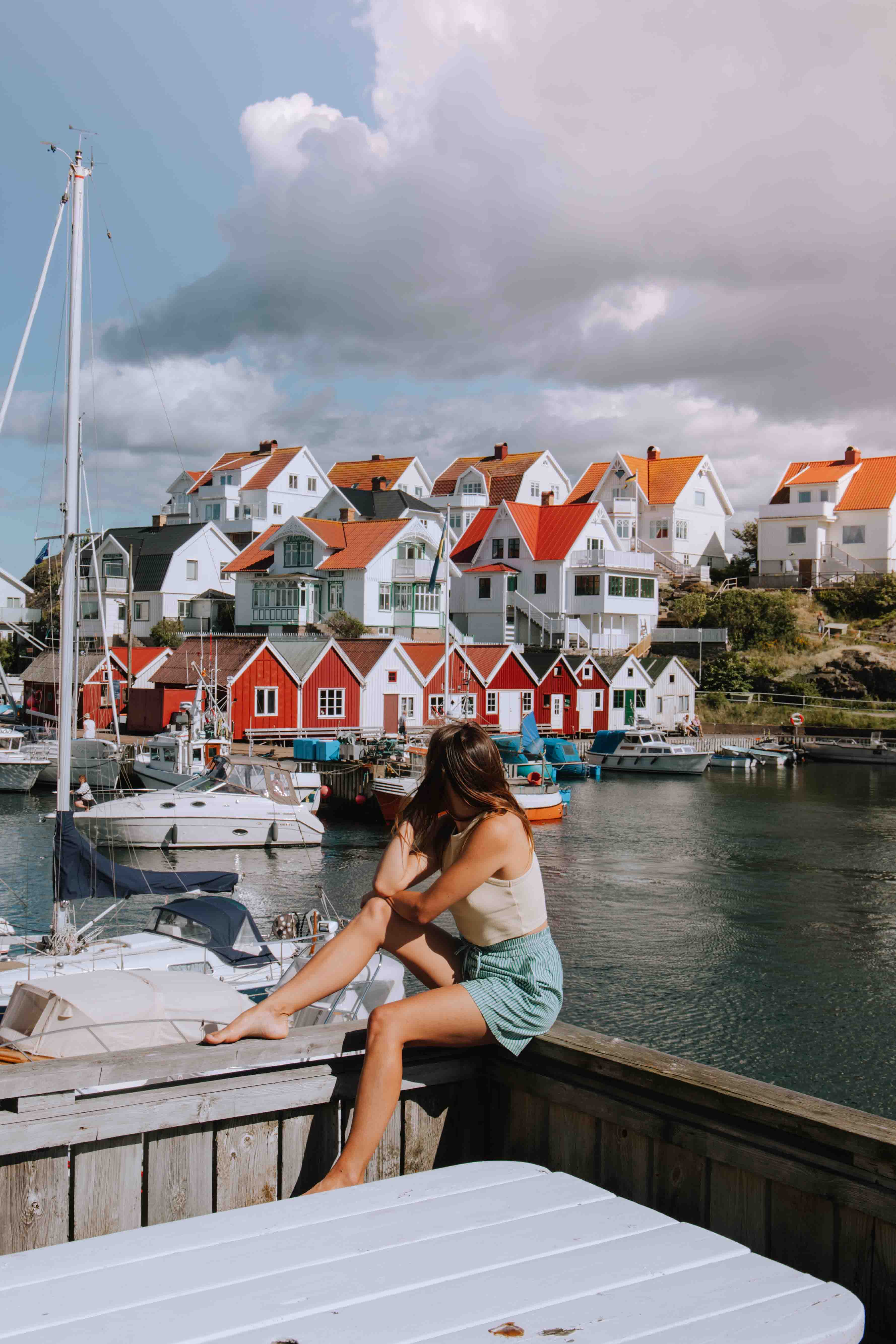 girl sat infront of view of picturesque fishing village åstol