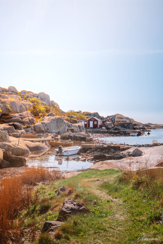 A small harbour with ocks and a grass walkway. In the harbour is a small white moto boat and a red wooden boat house