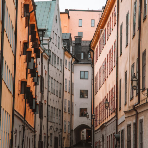 An alley way in Gamla Stan in Stockholm with a white house and tunnel at the end