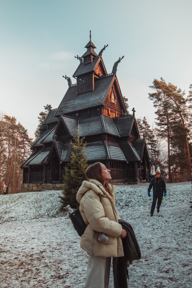girl standing outside the stave church in teh norwegian folk museum in oslo