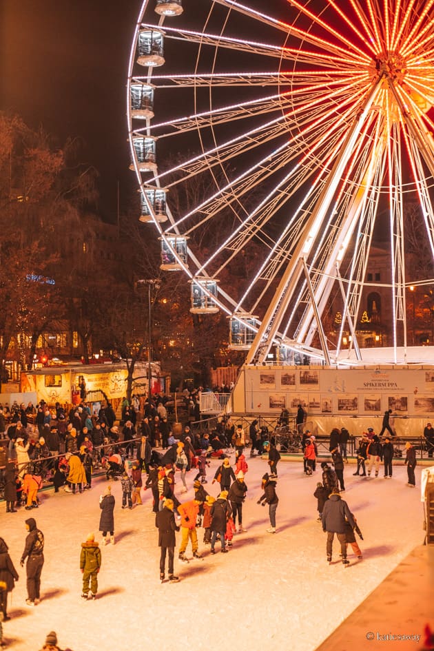 people ice skating in the ice rink at spikersuppa christmas market with a ferris wheel in the background