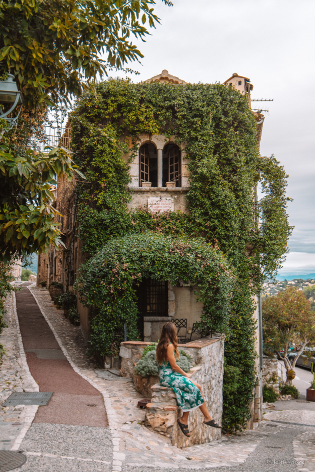 girl sitting infornt of a house covered in clematis in st paul de vence historic medieval city