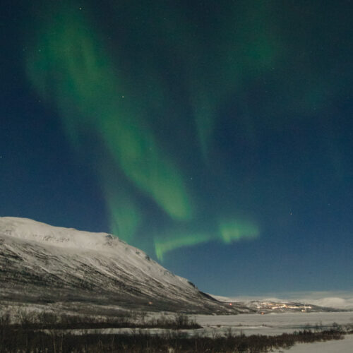 northern lights looking over abisko snowy winter mountains