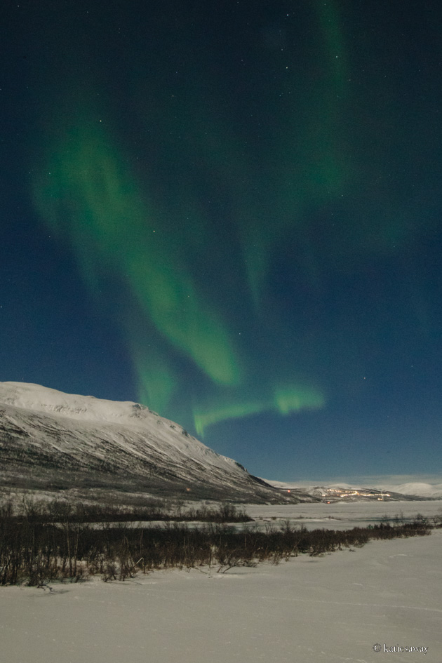 northern lights looking over abisko snowy winter mountains