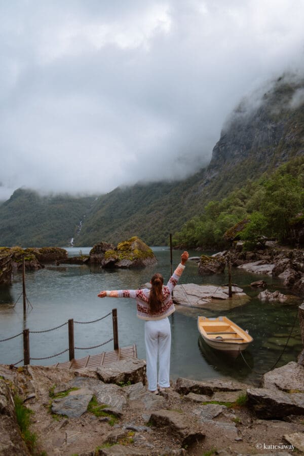 A person standing by Bondhusvatnet lake with a yellow row boat and view of the glacier