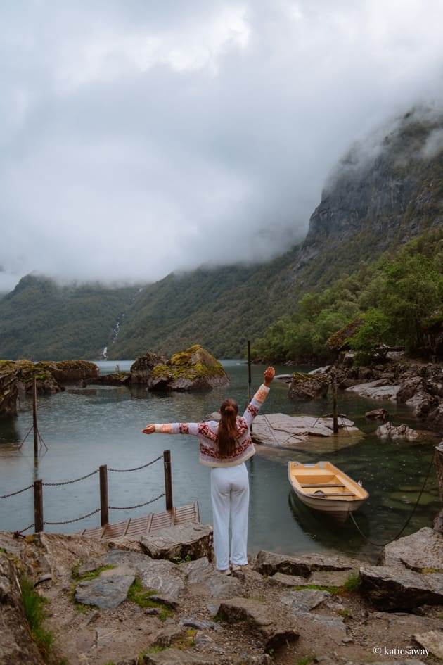 A person standing by Bondhusvatnet lake with a yellow row boat and view of the glacier